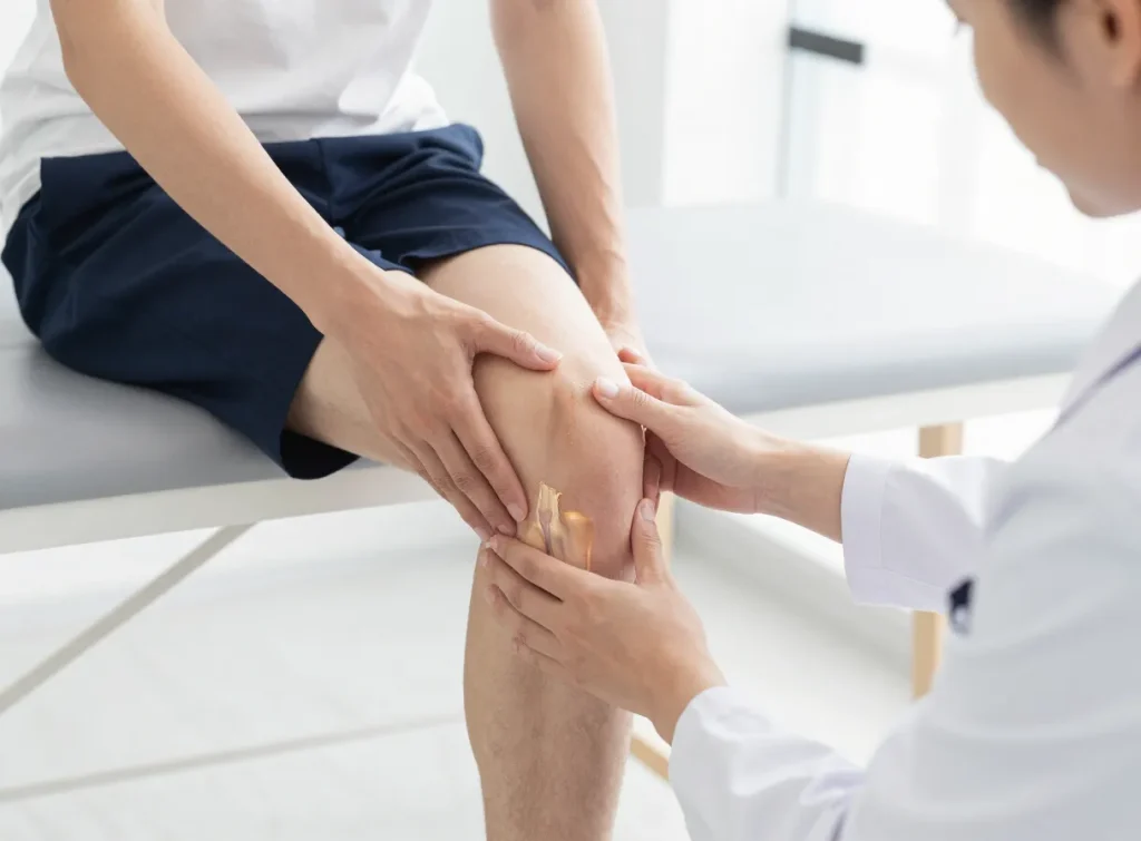 A physiotherapist assessing a patient's knee movement and kneecap tracking in a bright clinic room